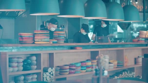 Kitchen counter with stacked dishware and the staff cooking — Stock Video