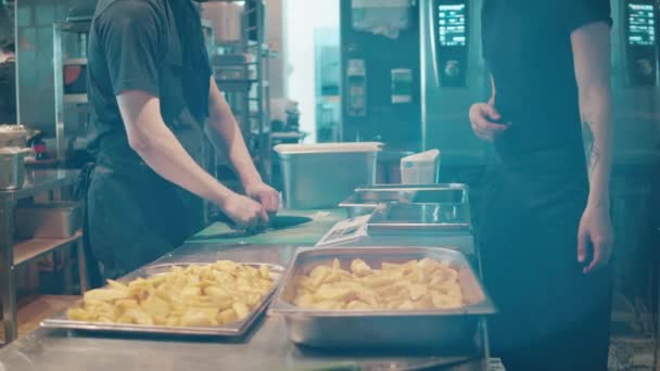 Trabajador de la cocina está poniendo una bandeja con patatas en el horno — Vídeo de stock