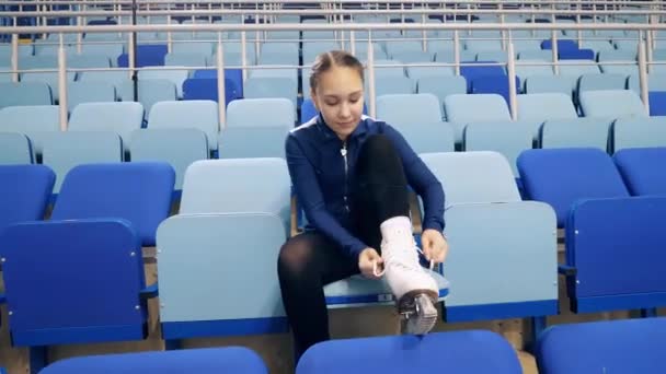 Jong meisje is veters omhoog haar schaatsen schoenen op de tribunes — Stockvideo