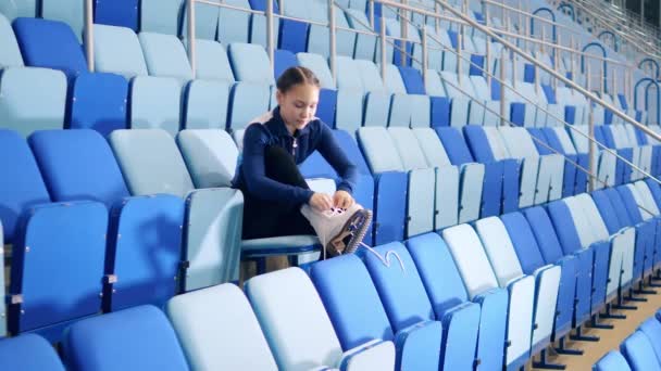 Kunstschaatser rijgt de schoenen op de tribune. — Stockvideo