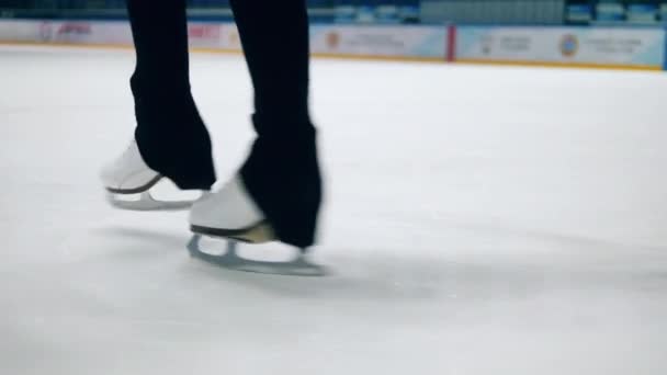 Zbliżenie nogi sportowców w łyżwach buty podczas przędzenia — Wideo stockowe