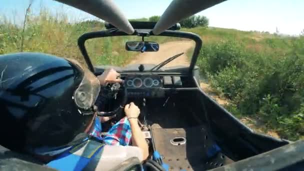 Föraren vid ratten i en racerbil rider genom terrängen — Stockvideo