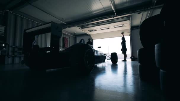 Mechanicy zamykają garaż z samochodem wyścigowym w środku — Wideo stockowe