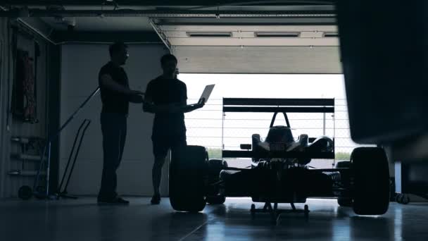 Garaje con mecánicos mirando el coche de carreras — Vídeo de stock