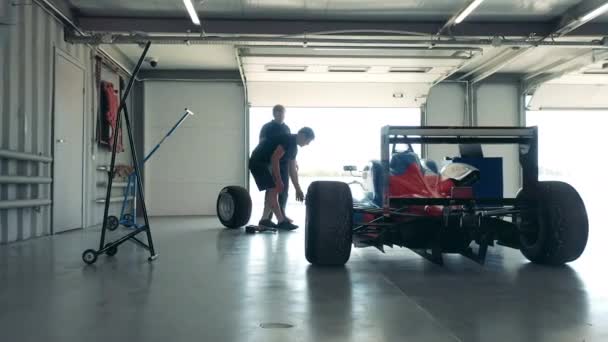 専門家はガレージでレースカーのホイールを固定しています — ストック動画