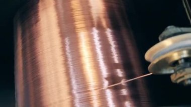Üzerinde yeni üretilen bakır kablo bulunan dönen bir makara.