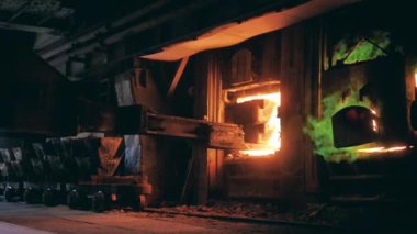 Dökümhane yükleyicisi kalıpları bir fırına daldırıyor.