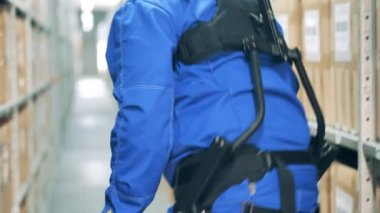 Ergoskeleton bir depo işçisinin bir kutuyu kaldırmasına yardım ediyor.