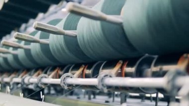Dikiş makaraları bir fabrika makinesi tarafından yakın planda yönetiliyor.