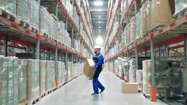 Empleado de almacenamiento está desplazando cajas con la ayuda de ergoskeleton — Vídeos de Stock