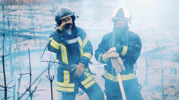 Dos bomberos de pie en las nubes de humo — Vídeo de stock