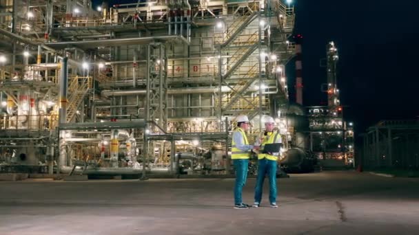 Två inspektörer pratar om vid oljeraffinaderiet sent på kvällen. — Stockvideo
