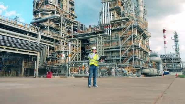 Ingeniero de refinería está hablando a través de una radio portátil en las instalaciones — Vídeo de stock