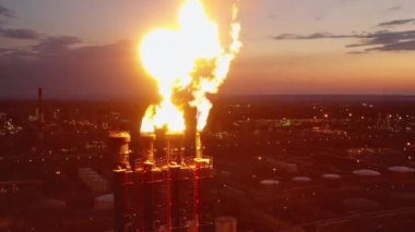 Petrol rafinerisinin işaret fişekleri gün batımında alev saçıyor.