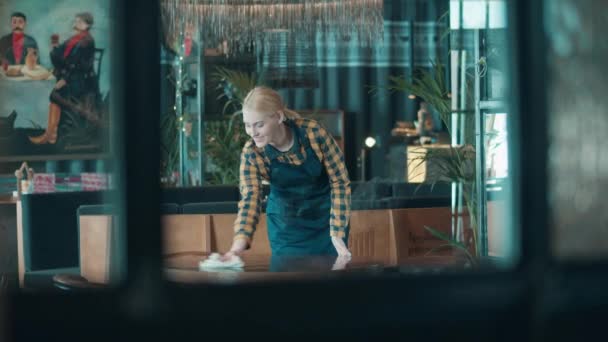 Офіціантка щаслива під час витирання столу в кафе — стокове відео