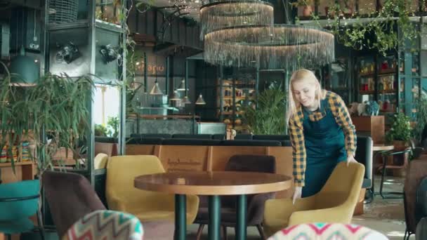 Весела офіціантка перестановка меблів в ресторані — стокове відео