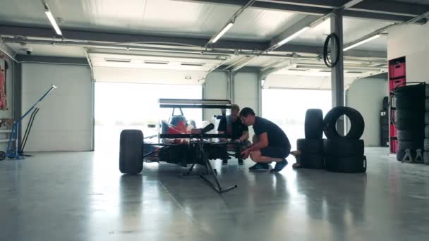 Maintenance specialists are inspecting the frame of the racing car — Stock Video