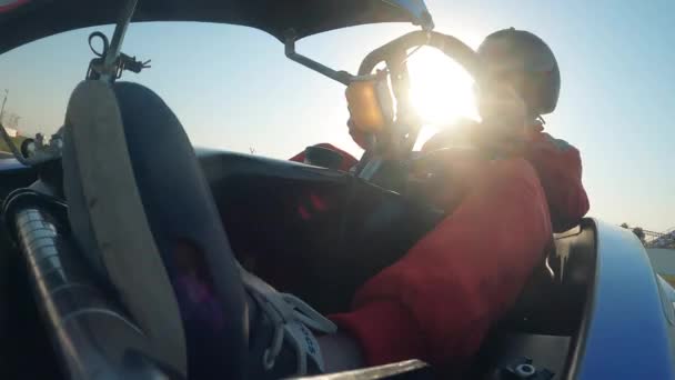 Mężczyzna kierowca siedzi wewnątrz wózka wyścigowego i zarządza nim — Wideo stockowe
