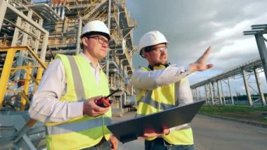 Fabrikadaki modern endüstriyel işçiler. İki rafineri mühendisi birlikte planları tartışıyorlar.