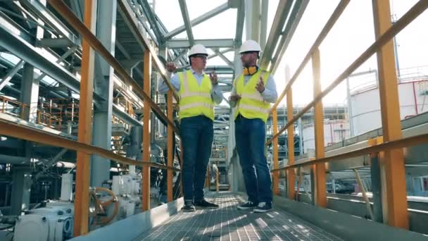 Rekan kerja laki-laki mendiskusikan konstruksi kilang minyak — Stok Video