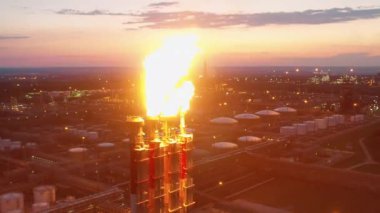Rafineri gazları ve fabrika inşaatları gün batımında çekiliyor. İklim değişikliği kavramı.