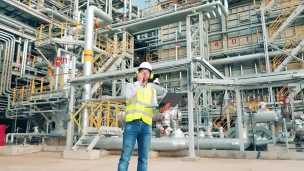 Oil refinery specialist is using gadgets for communication at work — Stock Video