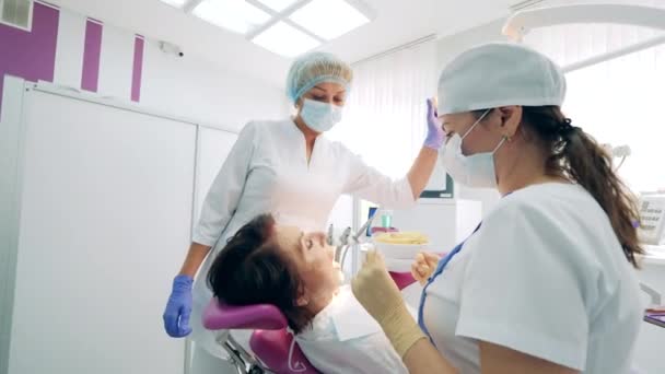 Dentistas estão fixando pacientes do sexo feminino dentes — Vídeo de Stock