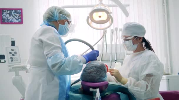 Стоматологи работают с пациентом в клинике — стоковое видео