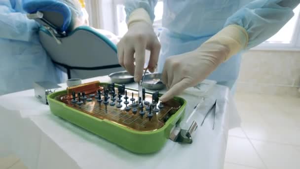 El dentista está eligiendo herramientas médicas para trabajar en el paciente — Vídeos de Stock