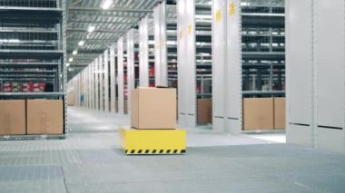 Otomatik araç depodan bir paket taşıyor.