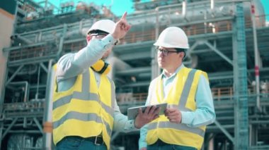 Modern bir endüstriyel tesiste iş arkadaşları konuşuyor..