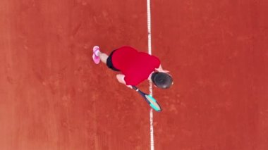 Tenis oynarken servis yapan bir adamın üst görüntüsü.