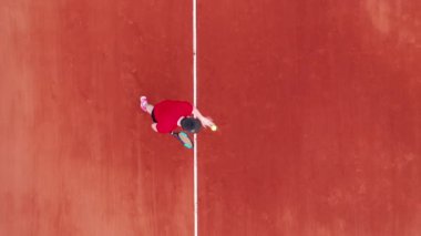 Bir adam yukarıdan bir manzarayla tenis topu servis ediyor.