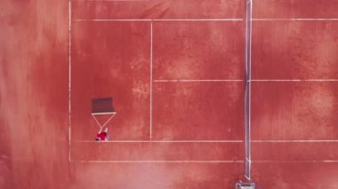 Bir adam tenis kortunu geçiyor, elinde ağ var.
