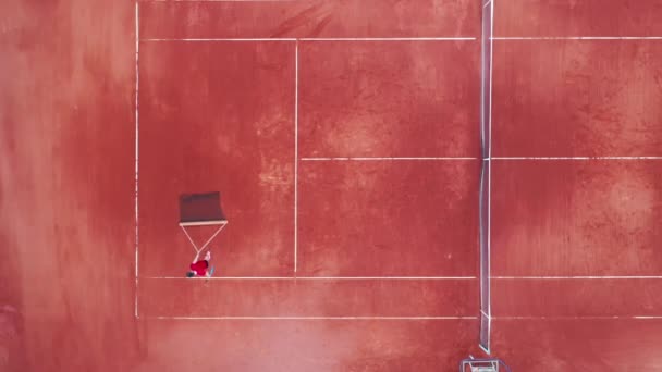 En man korsar en tennisbana med ett nät i en vy — Stockvideo