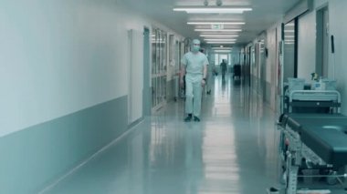 Hastane koridorunda sağlık görevlileri yürüyor.