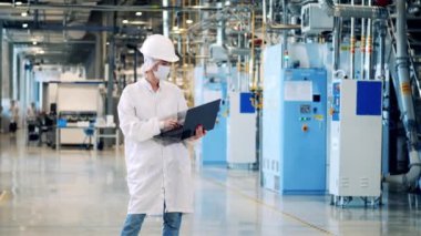 Dizüstü bilgisayarı olan kadın bir fabrika uzmanı gözlemler yapıyor.