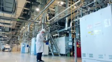 Fabrika uzmanı boruları ve ekipmanları inceliyor.