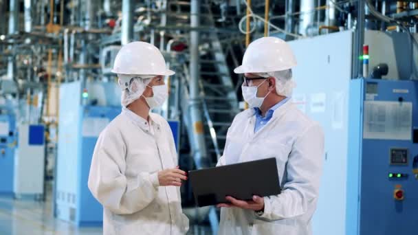 Two factory workers in lab coats are talking. Engineers, teamwork, modern factory facility. — Stock Video