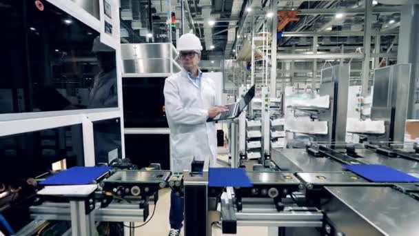 El trabajador de la fábrica está observando células solares moviéndose a lo largo del transportador — Vídeos de Stock