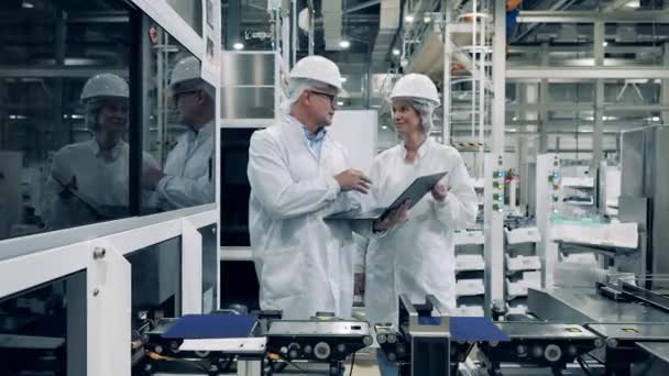 Ingenieros modernos en una fábrica. Dos especialistas están hablando junto al transportador de células solares — Vídeos de Stock