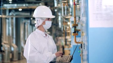 Fabrika uzmanı bir dizüstü bilgisayar ve dolap paneli kullanıyor.