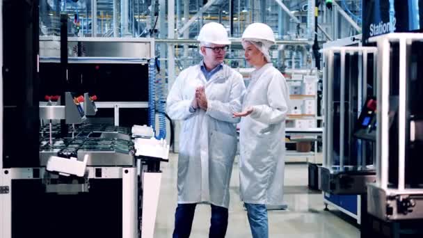 2人の専門家が太陽電池工場で機械を観察しています。エンジニア、チームワーク、近代的な工場施設. — ストック動画