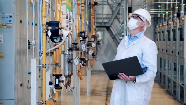 Mužský dělník v laboratorním plášti pozoruje tovární trubky — Stock video