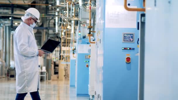 Trabajador de fábrica en una bata de laboratorio está manejando un gabinete — Vídeos de Stock