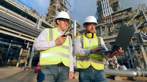 Специалисты по нефти используют гаджеты на заводе — стоковое видео