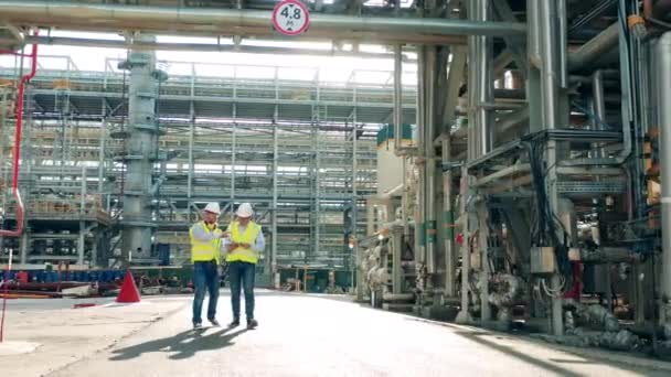 Tuberías de la planta de tratamiento de aceite con dos inspectores que pasan por — Vídeos de Stock