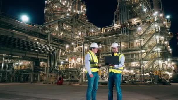 Gli ingegneri del campo petrolifero discutono alla fabbrica di notte. — Video Stock