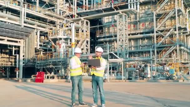 Рабочие партнеры разговаривают в центре нефтеперерабатывающего завода — стоковое видео