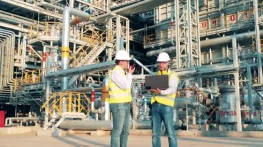 Petrol mühendisleri petrol işleme fabrikasında konuşuyorlar.